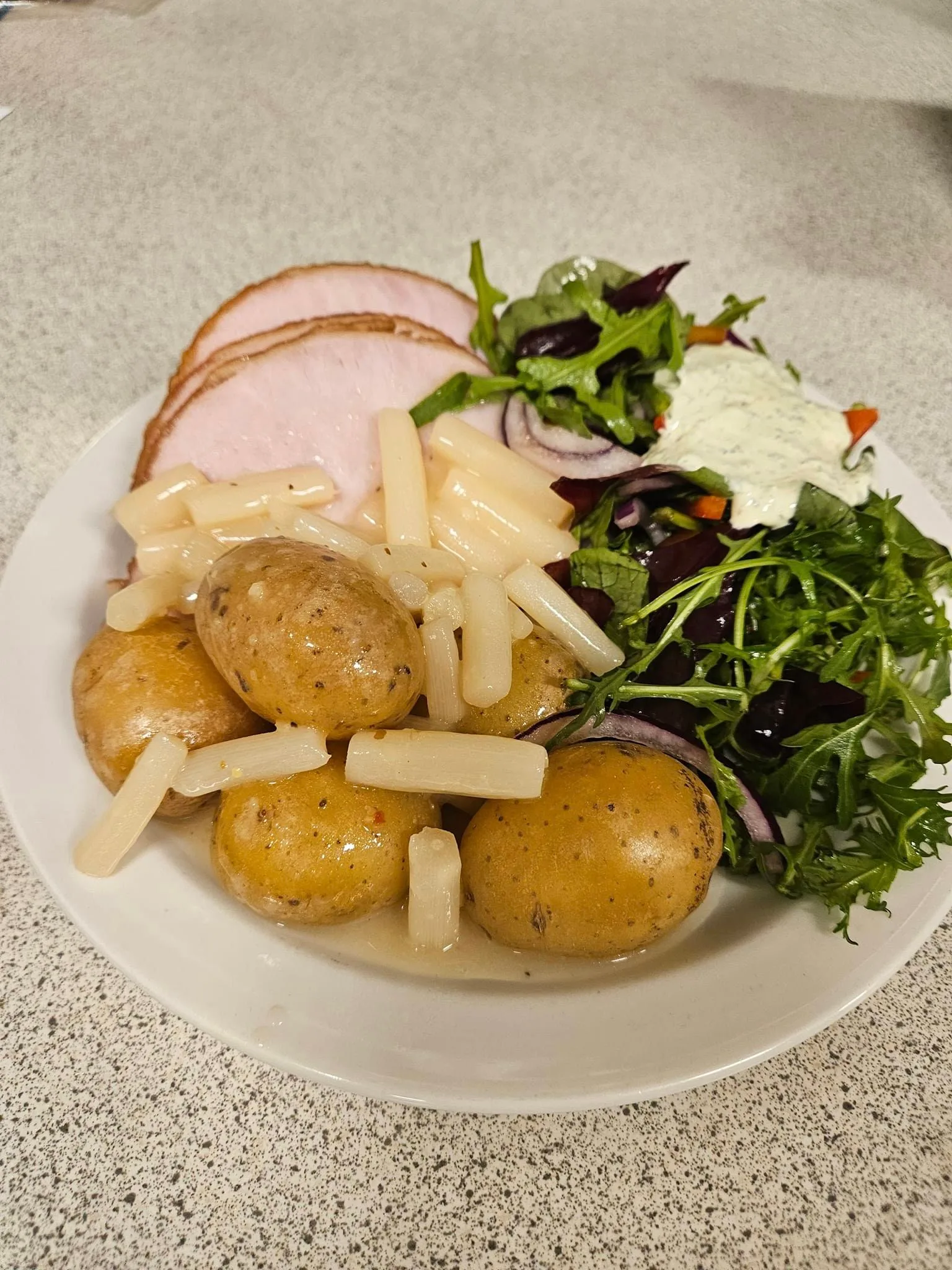 Ham, potatoes, salad, and pasta on plate.