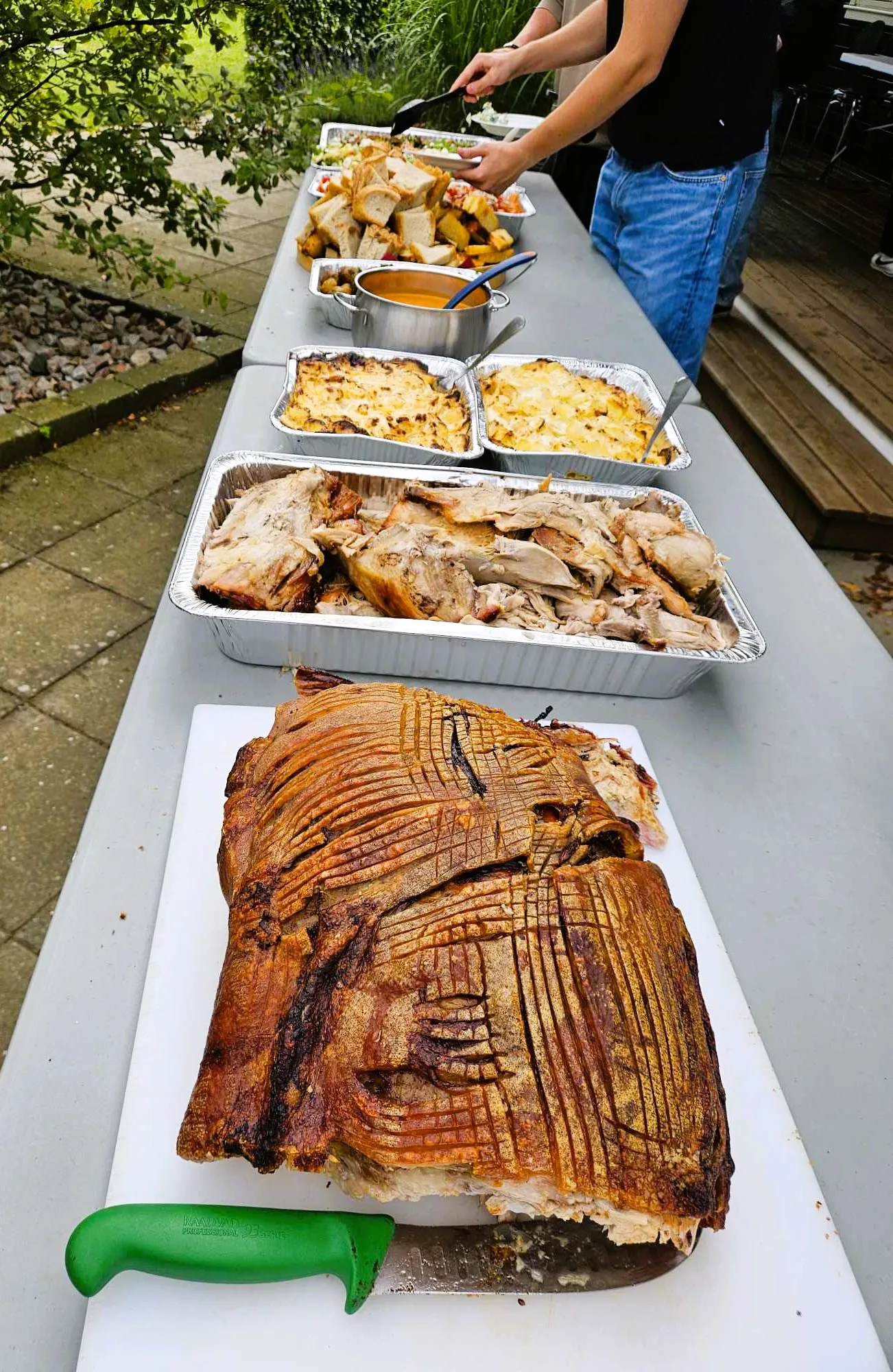 Outdoor buffet with various meats and sides.