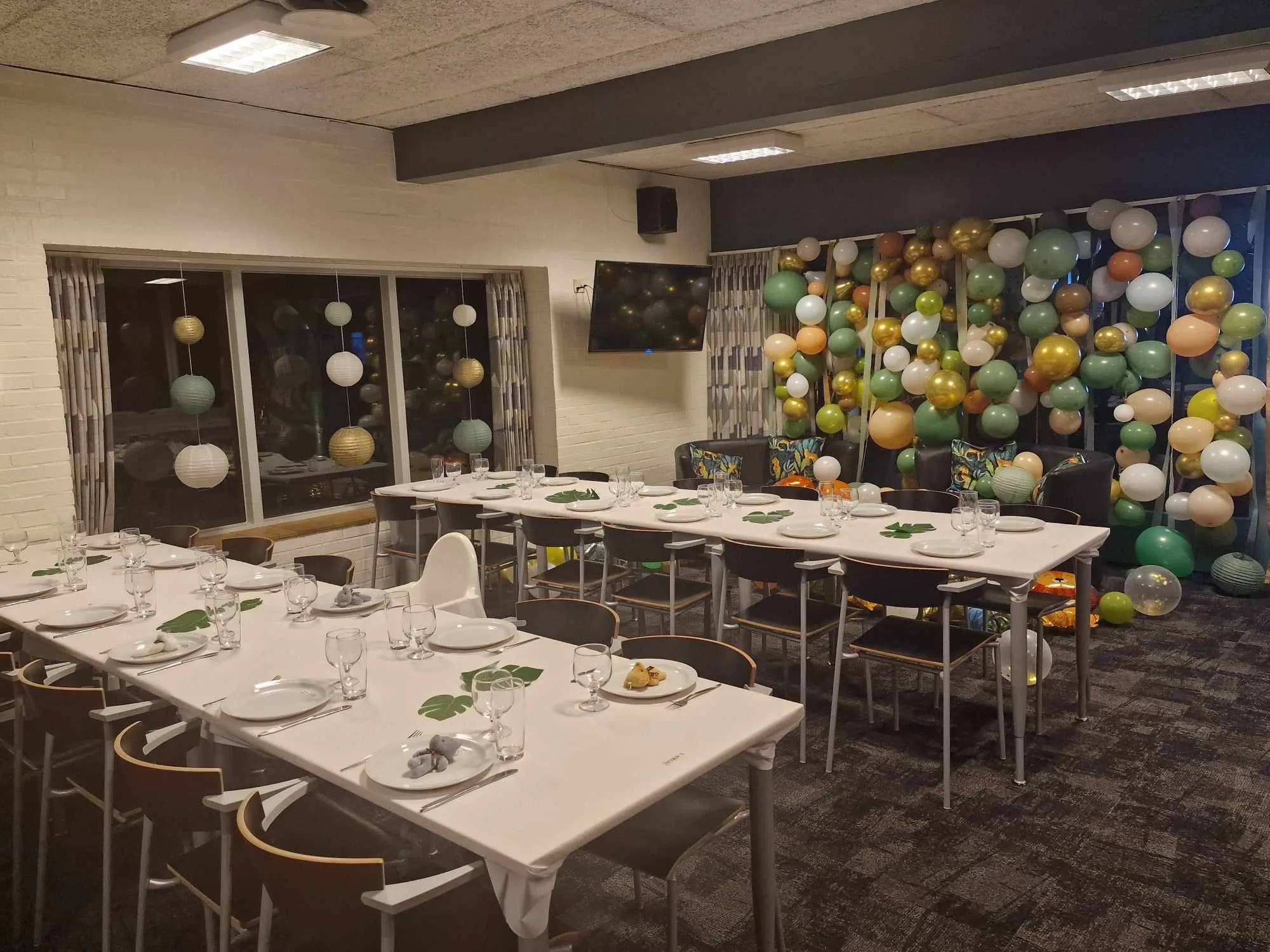Decorated party room with balloons and set tables.
