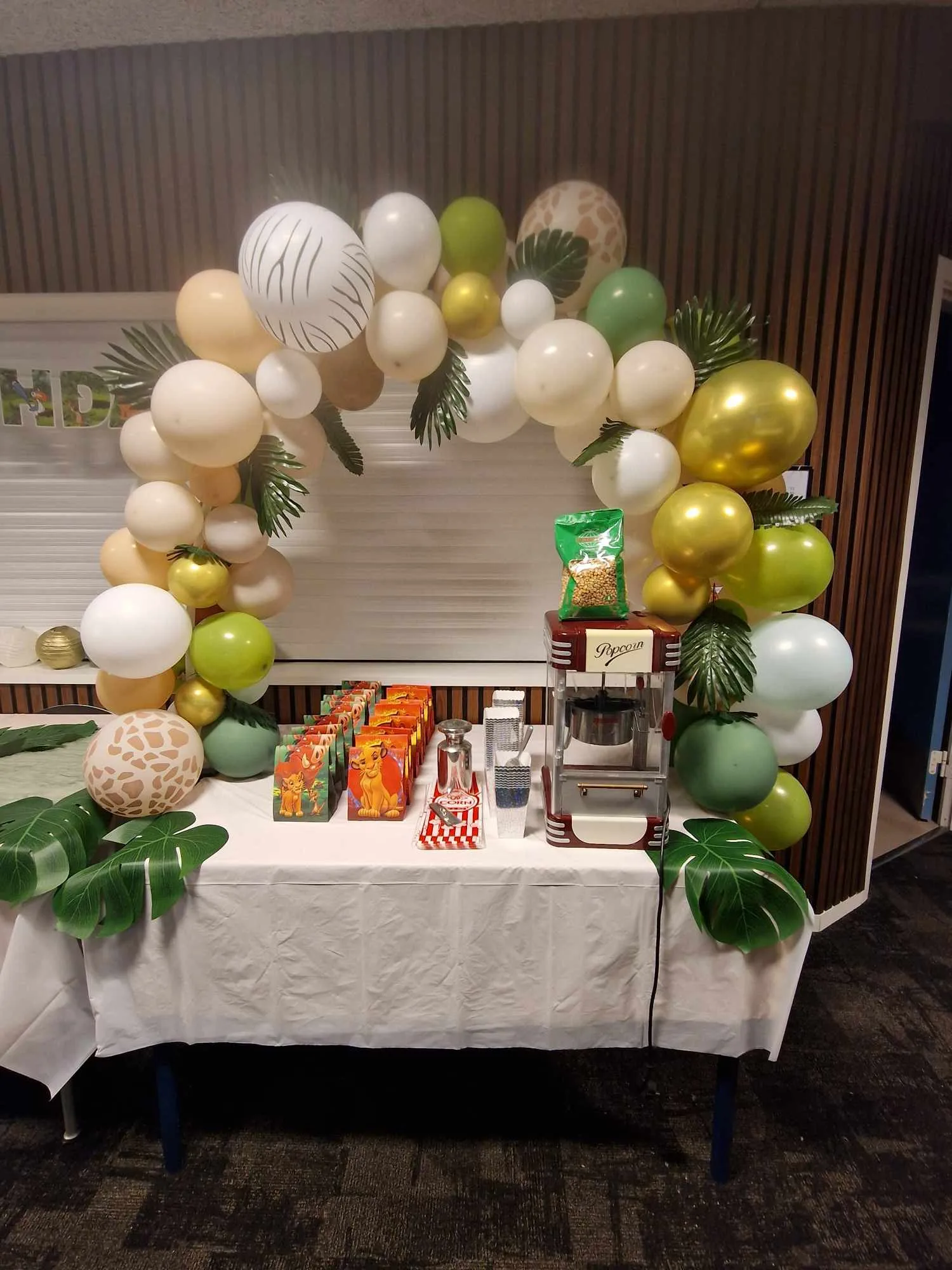 Party table with balloons and popcorn machine.