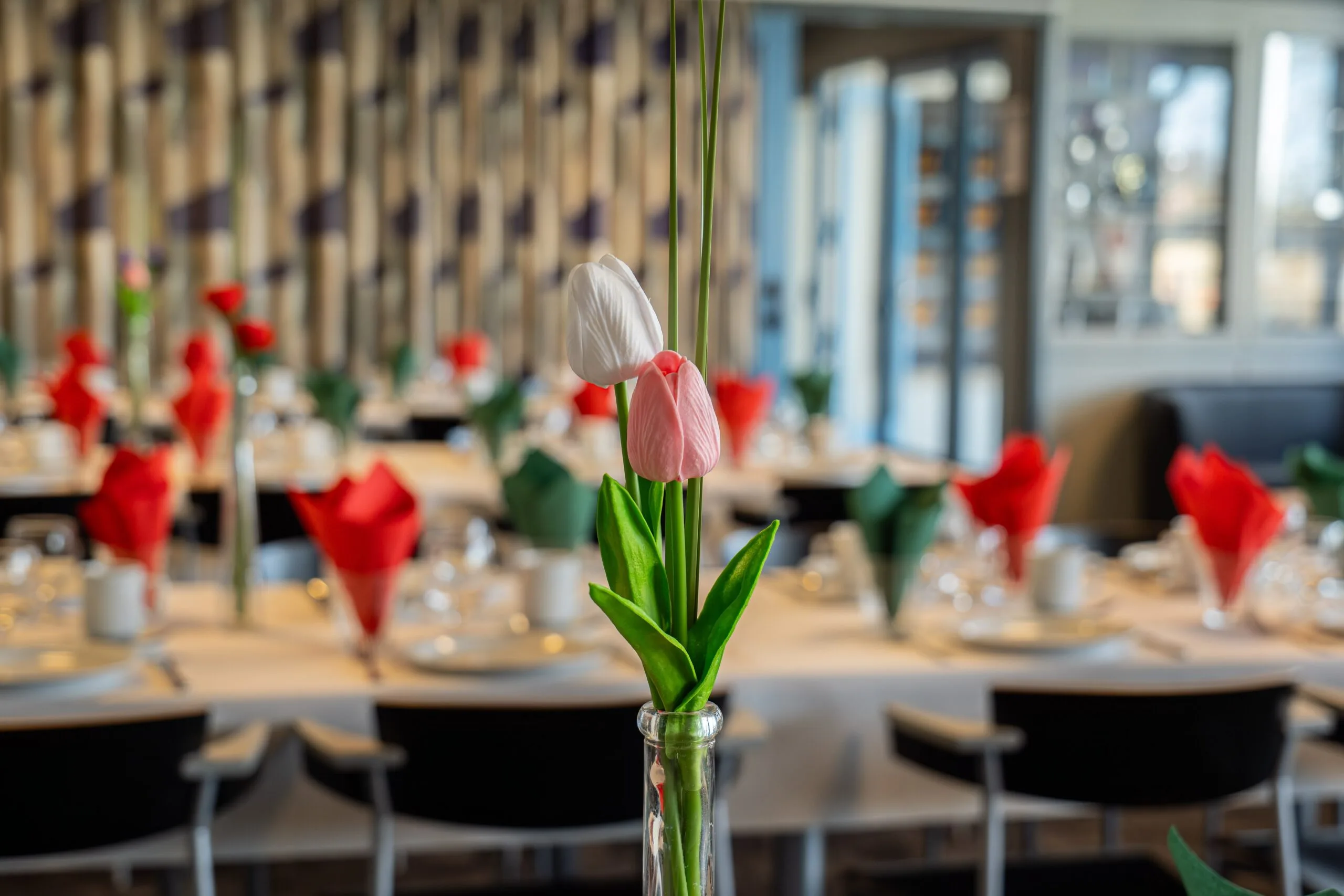 Tulips in vase on elegantly set restaurant tables