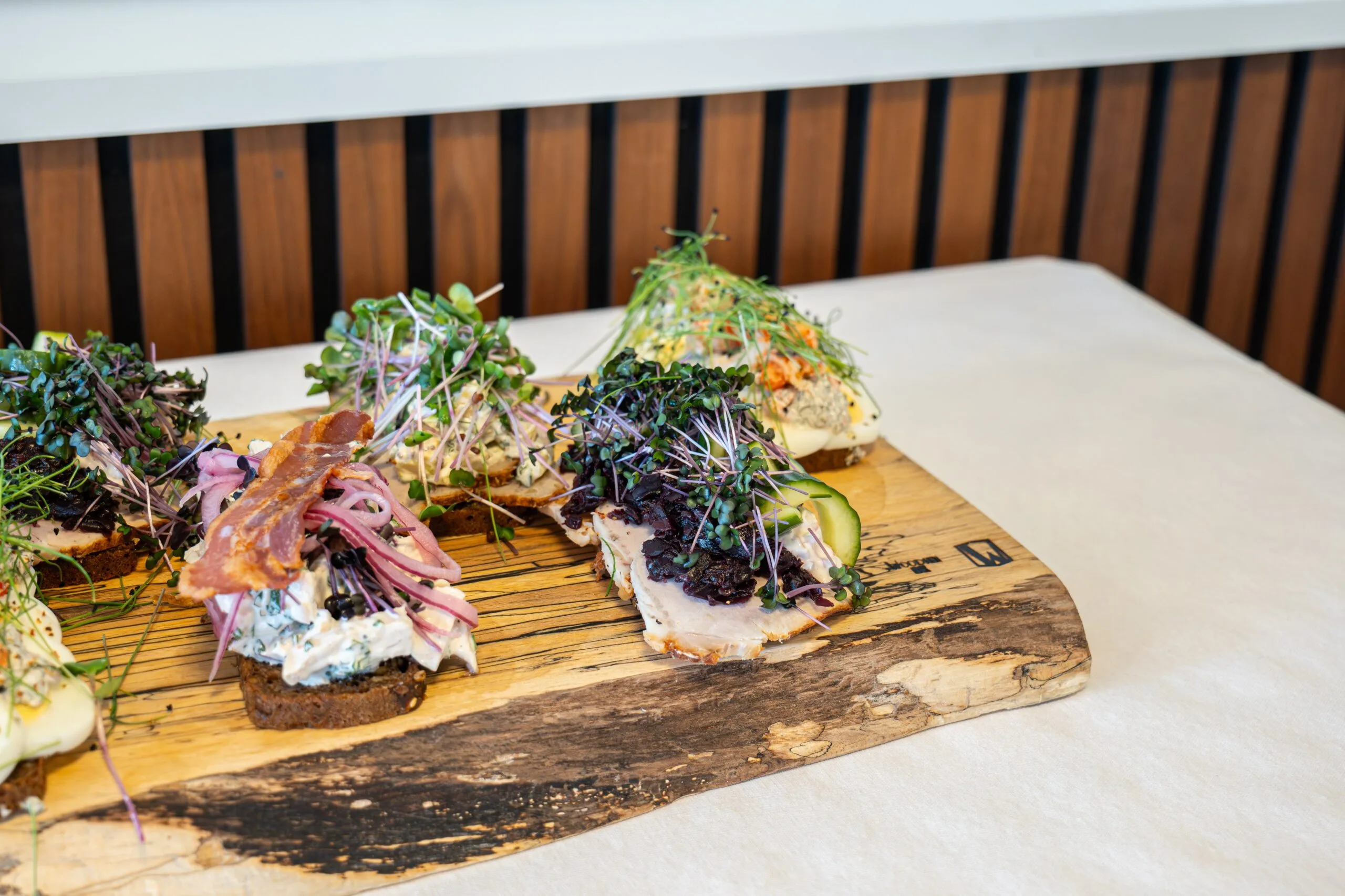 Open-faced sandwiches with assorted toppings on wooden board